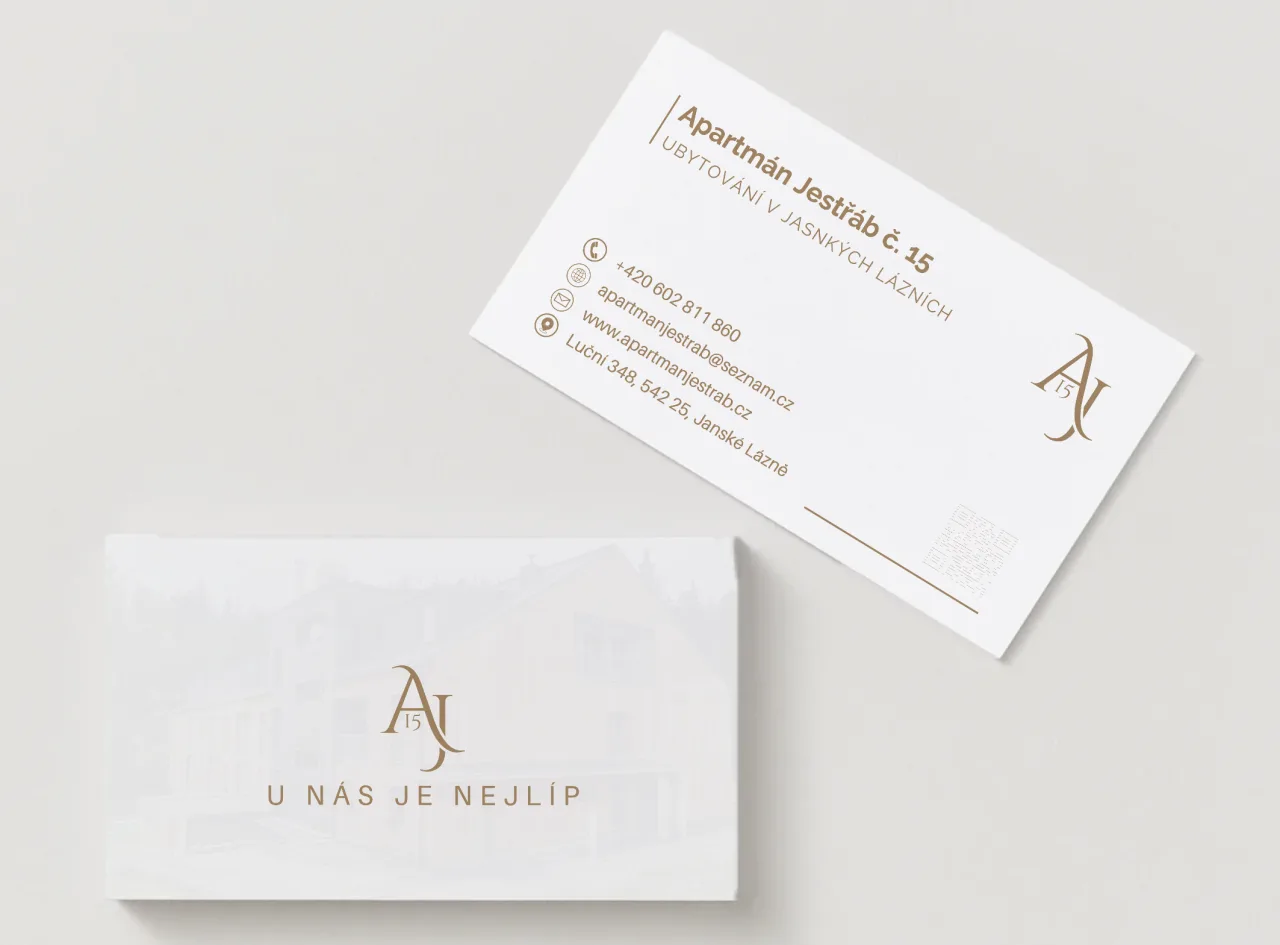 Business cards for Apartmán Jestřáb: a white front with the gold AJ15 monogram and the tagline U nás je nejlíp, and a back with the apartment's contact details and a QR code.